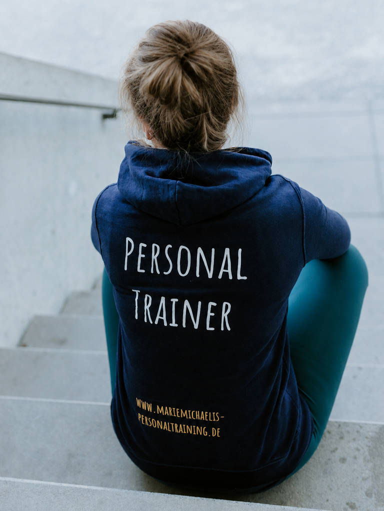 Personal Trainer sitzt auf der Treppe mit dem Rücken zur Kamera